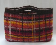 a plaid purse is sitting on a white surface with a black handle and yellow, red, and orange stripes