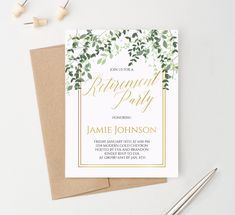 a white and gold engagement party card with greenery on the front, sitting on top of a brown envelope