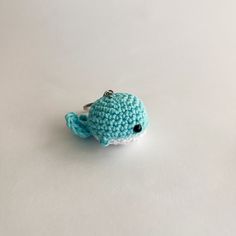 a small crocheted blue whale keychain on a white surface with black eyes