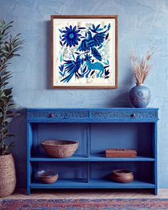 a blue shelf with two vases on top of it and a painting hanging above it