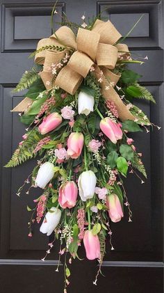 a wreath with pink and white flowers hanging on a door