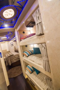 bunk beds in a small room with blue lights on the ceiling and round window above them