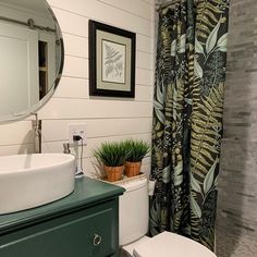 a bathroom with a toilet, sink and shower curtain in front of a mirror on the wall