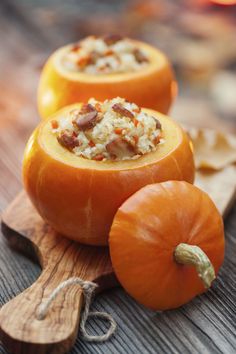 three pumpkins sitting on top of a wooden cutting board