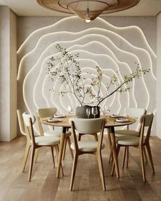 a dining room table with chairs and a vase on top of it in front of a white wall