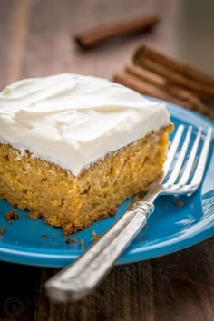 a piece of cake on a blue plate with a fork and cinnamon sticks next to it