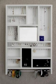 a white wall mounted jewelry rack with mirrors and earring hooks on it's sides