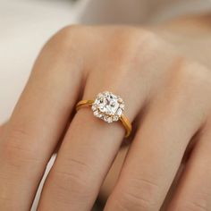 a woman's hand with an engagement ring on top of her finger and the other hand holding it