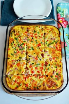 a square casserole dish on a table next to a plate and fork