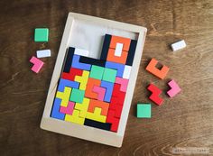 a wooden frame filled with colorful blocks on top of a wooden table next to a pile of colored magnets