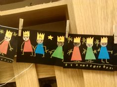 some paper cutouts are hanging from clothes pins with crowns on them and one is wearing a crown