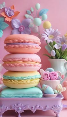 macaroons are stacked on top of each other in front of flowers and vases