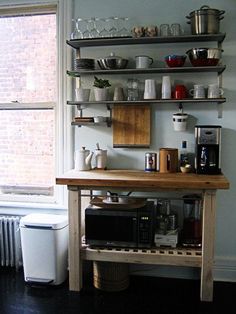 a kitchen area with a microwave, toaster oven and shelves filled with pots and pans