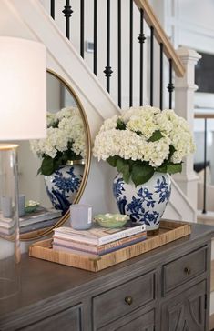 two blue and white vases sitting on top of a dresser next to a mirror