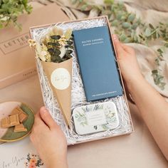 a person holding an ice cream cone with flowers in it and a book on the table