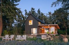 a black house sitting on top of a lush green field next to trees and grass