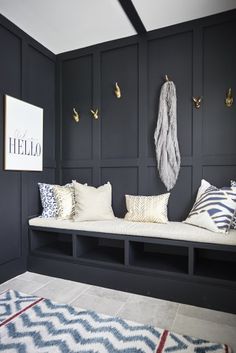 a room with black walls, white and blue pillows and gold hooks on the wall