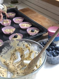 blueberries and cupcakes are being prepared in muffin tins