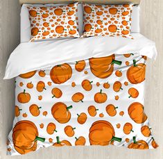 a bed with orange pumpkins on it and white comforter set in front of a wood floor