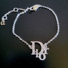 Never Worn, In Perfect Condition Vintage Authentic Christian Dior Logo Rhinestone Bracelet Made From Plated Silver Tone Metal Chain Featuring A Signature "Dior" Logo Jewelled With Swarovski Crystals And Finished With A Lobster Closure. Luxury White Gold Bracelets With Rhinestones, Luxury White Gold Bracelet With Rhinestones, Luxury Diamond White Bracelets With Rhinestones, Designer White Gold Bracelet With Diamond Accents, Designer White Gold Diamond Bracelet With Accents, Luxury Silver Diamond Bracelet For Party, Designer Silver Diamond Bracelet With Accents, Designer Silver Bracelets With Diamond Accents, Luxury Bracelets With Sparkling Stones