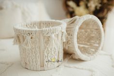 two knitted baskets sitting on top of a white tablecloth covered bed next to pillows