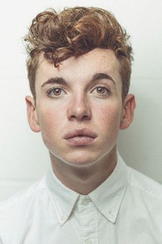 a young man with freckled hair is looking at the camera while wearing a white shirt