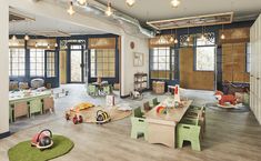 a room filled with lots of wooden furniture and green tables in front of large windows