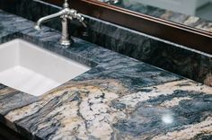 a marble counter top in a bathroom with a white sink and chrome faucet