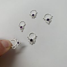 a person is holding five different types of silver earring settings on a white surface