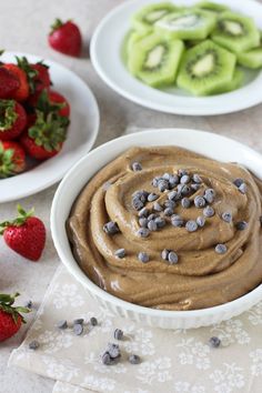 two bowls filled with chocolate pudding next to some sliced strawberries and kiwis