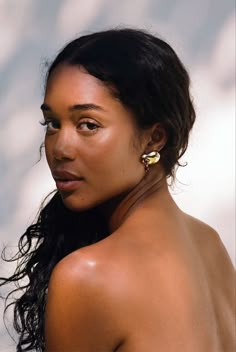 a close up of a woman with no shirt on wearing earring and looking off to the side