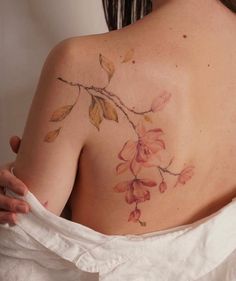 the back of a woman's shoulder with flowers painted on her left arm and chest