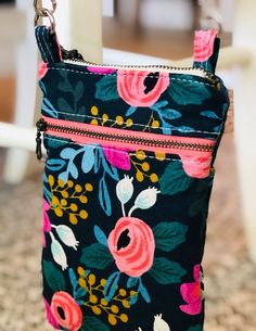 a floral purse with zippers hanging from the handle on a chair in front of a table