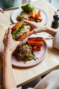 two plates with sandwiches and sweet potato wedges sitting on a table next to each other