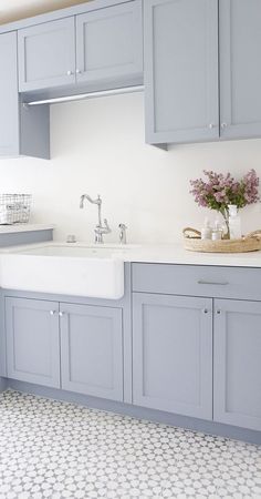 a kitchen with gray cabinets and white tile flooring on the counter top, along with a sink and dishwasher