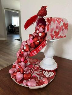 a heart shaped mailbox is decorated with pink and red hearts on a wooden table