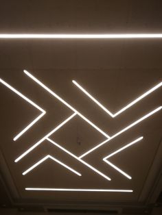 the ceiling is lit up with white lights and lines on it's sides, as well as an arrow symbol