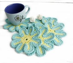 a coffee cup sitting on top of a table next to a crocheted doily