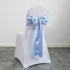 a white chair with a blue bow tied to it's back and seat cover