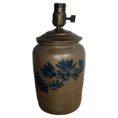 a ceramic urn with blue leaves painted on the side and a brass faucet