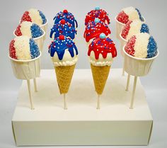 four ice cream cones decorated with red, white and blue sprinkles on sticks