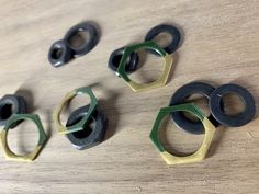 four pairs of black, green and gold rings on a wooden table with wood grained surface