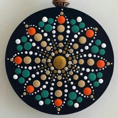 a black circular object with colorful circles and dots on the top, hanging from a wall