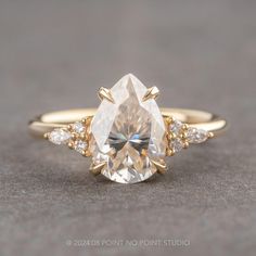 an engagement ring with a pear shaped diamond surrounded by three smaller round brilliant cut diamonds