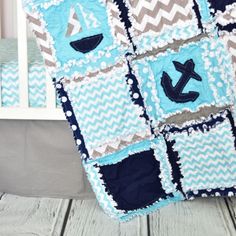 a blue and gray baby quilt on a white crib