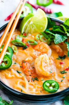 a black bowl filled with shrimp and green peppers next to chopsticks on top of a table