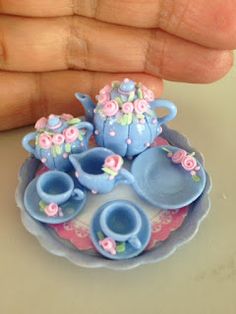 a hand is holding a miniature tea set