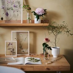 some flowers are sitting in vases on a table next to two pictures and a book