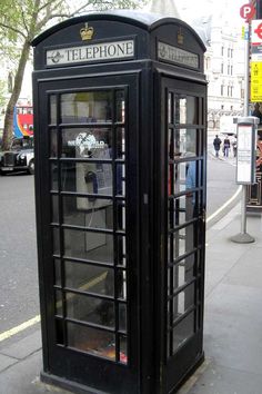 a black phone booth sitting on the side of a street