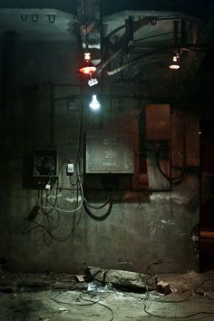 an old room with some wires and lights on the wall, in front of a telephone box